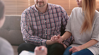 therapist taking notes while listening to a couple