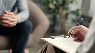 therapist taking notes while listening to patient